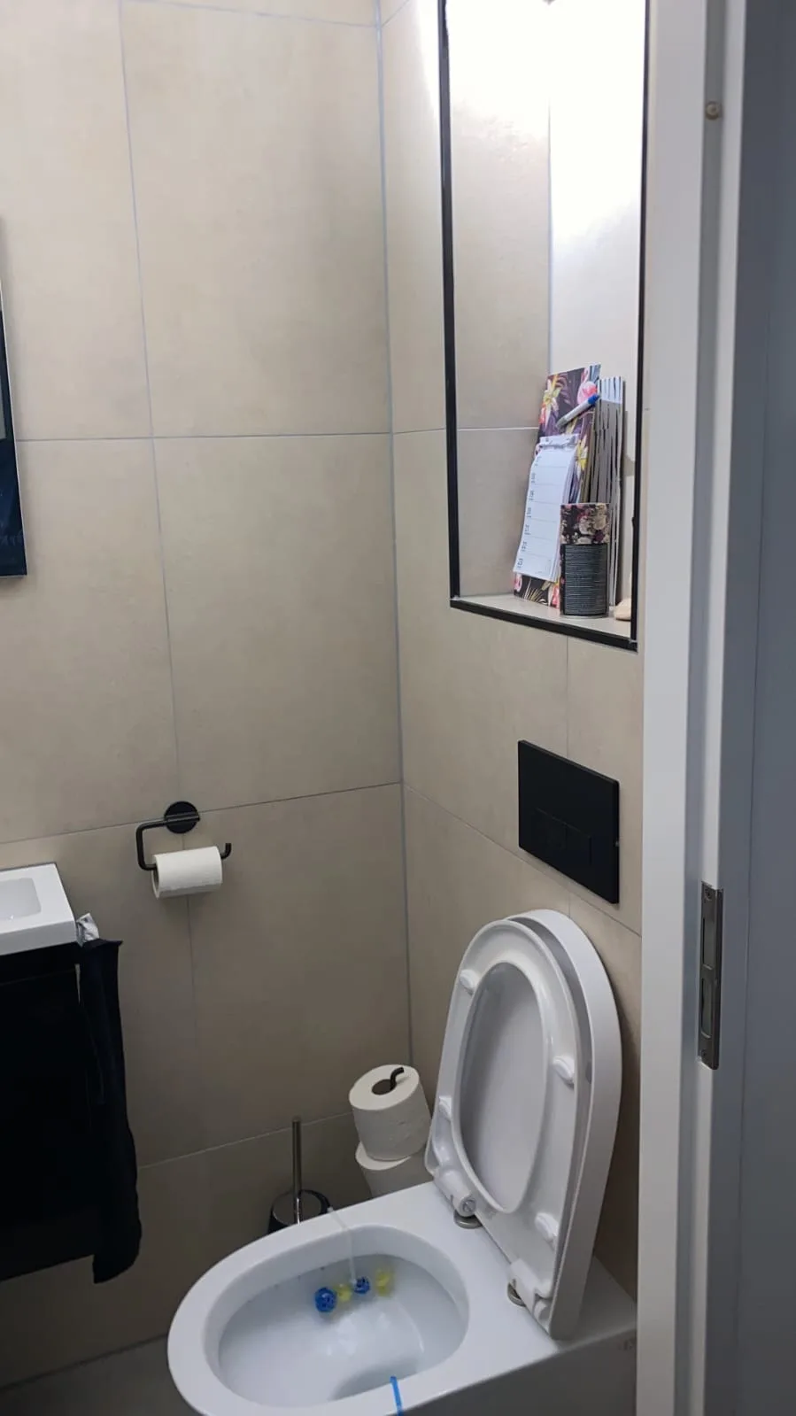 Toiletruimte met hangtoilet en zwarte bedieningsplaat