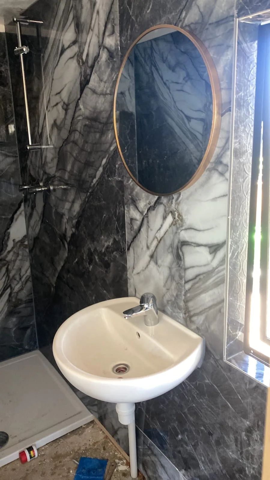 Wastafel voor een marmerlook wand met ronde spiegel