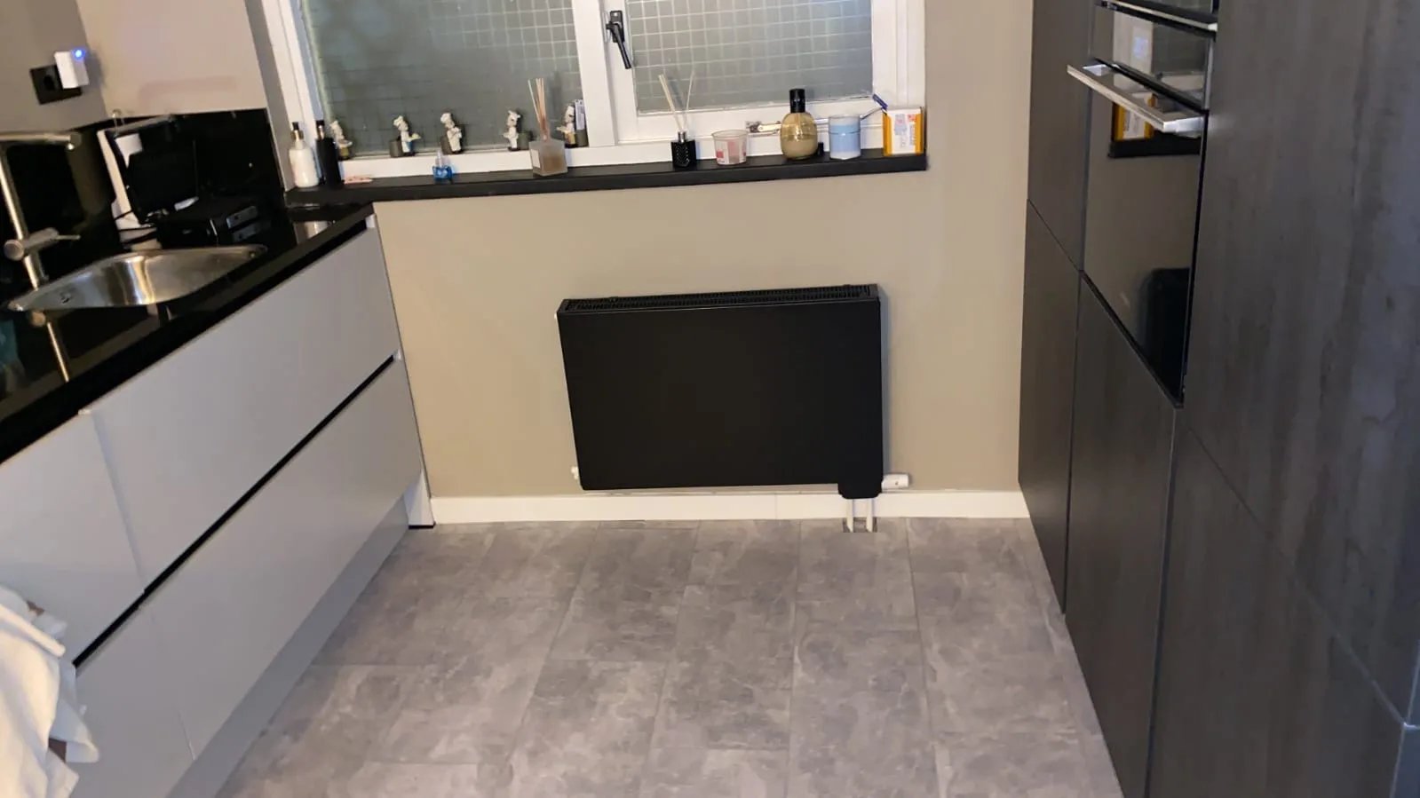 Zwarte radiator onder het keukenraam
