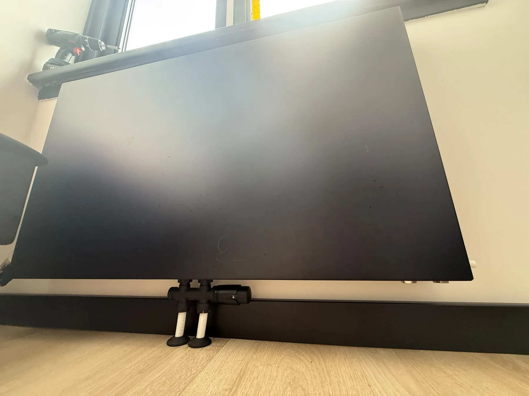 Zwarte radiator met onderaansluiting vanuit de vloer