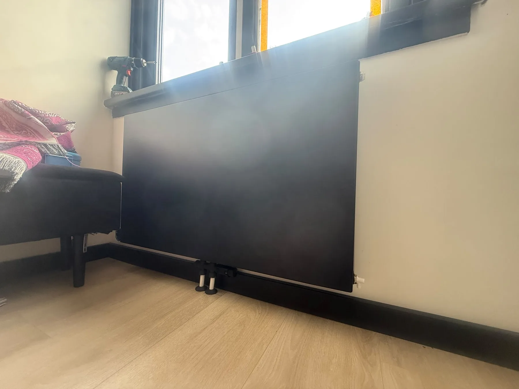 Zwarte paneelradiator onder het raam in de woonkamer
